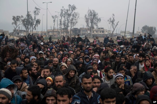 Displaced Iraqi men, fleeing fighting between Iraqi security forces and Islamic State militants, wait for a security check before being transferred to a camp on the western side of Mosul, Iraq, March 23, 2017.