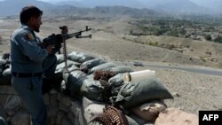 An Afghan security force member stands at a checkpoint, set alight by Islamic State fighters during overnight clashes, in the Achin district of eastern Nangarhar province, Sept. 28, 2015.