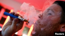 FILE - A customer puffs on an e-cigarette at the Henley Vaporium in New York City, Dec. 18, 2013.