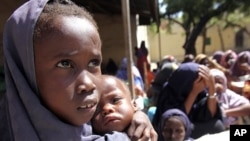 An internally displaced Somali girl carries her sibling as they wait to collect food relief from the World Food Program (WFP) at a settlement in Mogadishu August 7, 2011.