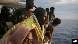 FILE - Migrants look out from the deck of the Spanish NGO ProActiva Open Arms vessel as they wait to reach the Italian coast on the Mediterranean Sea, a day after being rescued off the Libyan coast, Sept. 7, 2017.