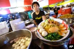 A street food vendor displays a bowl of Bamee Jom Palang, or "Power Noodles", at one of the most crowded food stalls at Rotfai Market in Bangkok, Thailand.