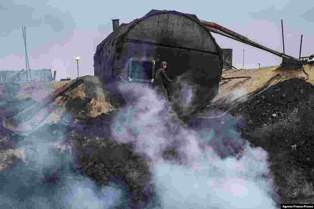 A worker is seen at a primitive oil refinery center in the town of al-Qahtaniya in Syria's Kurdish-controlled northeastern Hasakah province, near the border with Turkey, Nov. 15, 2021.