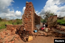 Ester Thoma cooks at her damaged house in the aftermath of Cyclone Idai, in the village of Cheia, which means "Flood" in Portuguese, near Beira, Mozambique April 1, 2019.