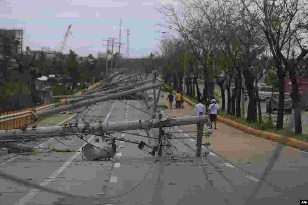 Residents walk past downed electric pylons in Talisay town, Cebu province, a day after Super Typhoon Rai pummeled the southern and central regions of the Philippines. 