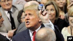 El republicano Donald Trump muestra un botón de campaña luego de hablar el domingo en Alabama.