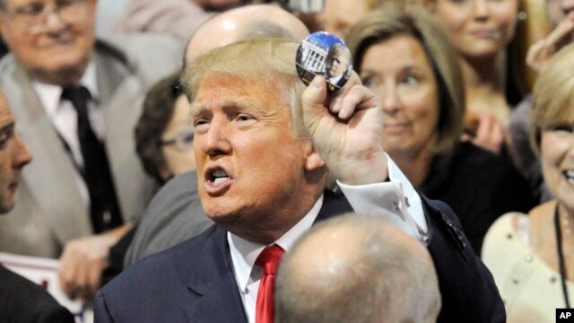 El republicano Donald Trump muestra un botón de campaña luego de hablar el domingo en Alabama.
