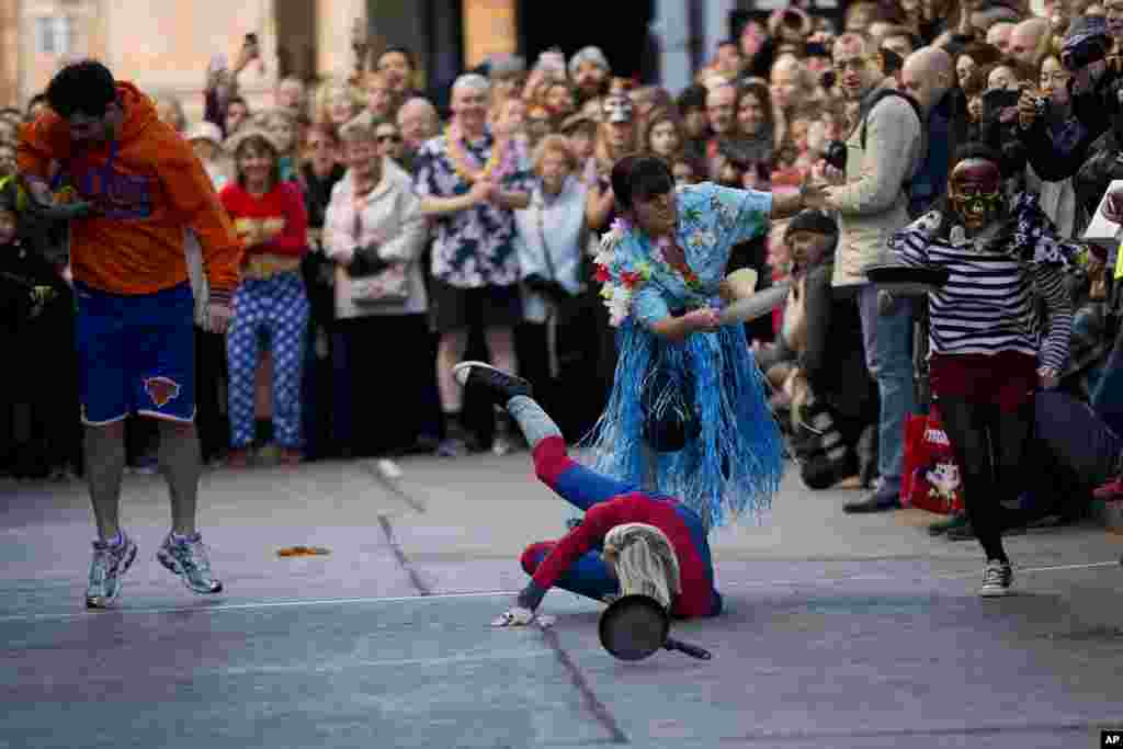 A participant falls during the fancy dress Great Spitalfields Pancake Race, off Brick Lane in east London.