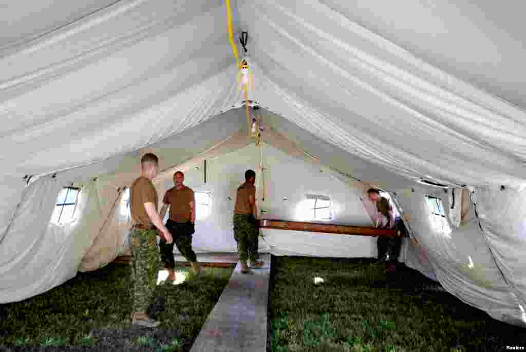 Members of the Canadian Armed Forces carry floorboards into the tents they erected to house asylum seekers at the Canada-United States border in Lacolle, Quebec, Aug. 9, 2017.