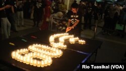 Relawan Earth Hour menyalakan lilin dalam seremoni di Kota Bandung, Jawa Barat, Sabtu malam, 30 Maret 2019.(Foto: Rio Tuasikal/VOA)