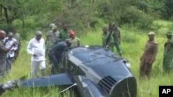 Menteri Pariwisata dan Sumber Daya Alam Tanzania Jumanne Maghembe dan para pejabat lainnya memeriksa bangkai helikopter di mana seorang pilot Inggris yang sedang melakukan usaha anti perburuan liar dibunuh.