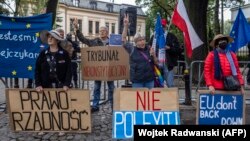 Demonstran memegang spanduk bertuliskan (dari kiri) "Rule of Law", "Inconstitutional Court", "No to Polexit" dan "EU Don't Back Down" saat mereka melakukan protes pada 31 Agustus 2021 di depan Mahkamah Konstitusi di Warsawa. (Foto: AFP/Wojtek Radwanski)
