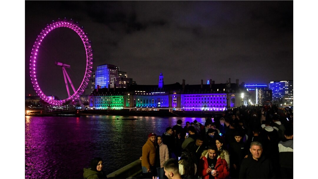 Orang-orang berkumpul di Westminster Bridge sementara London Eye terlihat di belakang, selama perayaan Malam Tahun Baru, saat penyebaran COVID-19 berlanjut di London, Inggris, 31 Desember 2021. (Foto: REUTERS/Toby Melville)