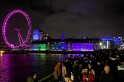 Orang-orang berkumpul di Westminster Bridge sementara London Eye terlihat di belakang, selama perayaan Malam Tahun Baru, saat penyebaran COVID-19 berlanjut di London, Inggris, 31 Desember 2021. (Foto: REUTERS/Toby Melville)