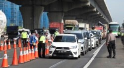 Para petugas kepolisian mengecek mobil-mobil di jalan tol Cikarang, Jawa Barat, untuk mencegah warga agar tidak pulang kampung di tengah pandemi virus corona, 24 April 2020.