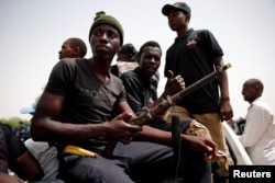 FILE - Members of a local militia, otherwise known as CJTF, sit in the back of a truck during a patrol in the city of Maiduguri, northern Nigeria, June 9, 2017.