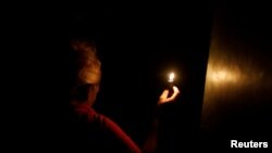 Seorang wanita menggunakan lilin saat memasuki rumah pada hari kedua pemadaman listrik di Caracas, Venezuela, 9 Maret 2019 (foto: Reuters/Carlos Jasso)