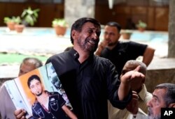 FILE - A grieving Iraqi father shows a poster of his dead son, who was an Iraqi soldier, in a Baghdad courtroom, July 8, 2014.