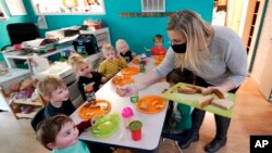 Amy McCoy serves lunch to preschoolers at her Forever Young Daycare facility, Monday, Oct. 25, 2021, in Mountlake Terrace, Wash. (AP Photo/Elaine Thompson)