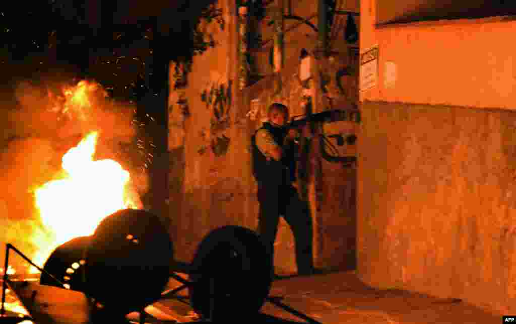 Polisi militer Brazil berdiri di antara benda yang terbakar dalam aksi protes di komplek Copacabana, Rio de Janeiro, Brazil.