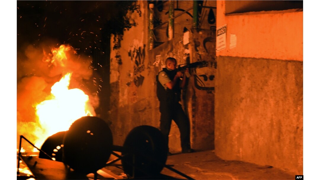 FILE - A military policemen stands in position during a violent protest in a favela next to Copacabana, Rio de Janeiro, April 22, 2014.
