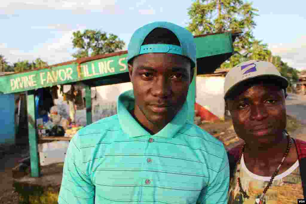 Isaiah (left) and his brother Bruder Jamal Williams in front of the small gas station where Jamal makes his living. Both of them say they feel sad that they must avoid contact with friends, shaking hands or even spending time with them, Monrovia, Liberia, Oct. 9, 2014. (Benno Muchler/VOA) 