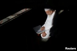 FILE - Abdul Barek Hajji, a Bengali Muslim, reads the Koran while waiting for the Maghrib sunset prayer during Ramadan at the Abu Bakr Mosque in Flushing, New York, May 31, 2017.