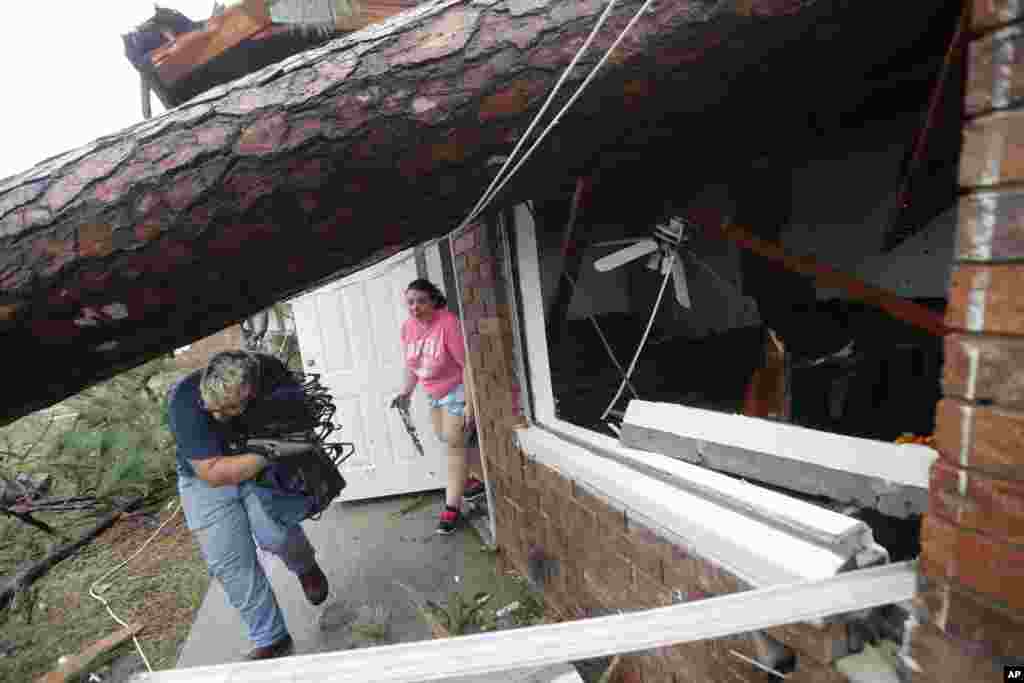 Megan Williams, left, and roommate Kaylee O'Brian take belongings from their destroyed home after several trees fell on the house during Hurricane Michael in Panama City, Fla., Oct. 10, 2018.