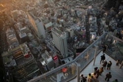 Turis mengambil gambar di tepi Shibuya Sky, Senin, 20 Januari 2020, di Tokyo. (Foto: AP)