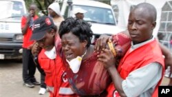 Red Cross staff console a woman after she viewed the body of a relative killed in Thursday's attack at a university in Garissa northeastern Kenya, at Chiromo funeral home, Nairobi, Kenya, Tuesday, April 7, 2015. Al-Shabab gunmen rampaged through a university in northeastern Kenya at dawn Thursday, killing scores of people in the group's deadliest attack in the East African country. (AP Photo/Khalil Senosi)