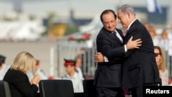 French President Francois Hollande (L) and Israeli Prime Minister Benjamin Netanyahu embrace during the official reception upon Hollande's arrival at Ben Gurion airport near Tel Aviv, Nov. 17, 2013.