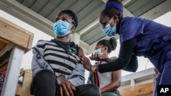 FILE - A nurse gives a shot of AstraZeneca coronavirus vaccine, donated by Denmark, to a woman at Mbagathi Hospital in Nairobi, Kenya, July 9, 2021. 