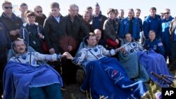 U.S. astronaut Thomas Marshburn, right, Russian cosmonaut Roman Romanenko, center, and Canadian astronaut Chris Hadfield, sit in chairs shortly after the landing of the Russian Soyuz TMA-07 space capsule, May 14, 2013.