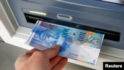 A 100 franc bank note is pulled from an ATM in Kreuzlingen, Switzerland on Jan. 16, 2015.