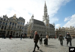 Police patrol through the Grand Place, as tourists wander in Brussels, Monday, March, 28, 2016.