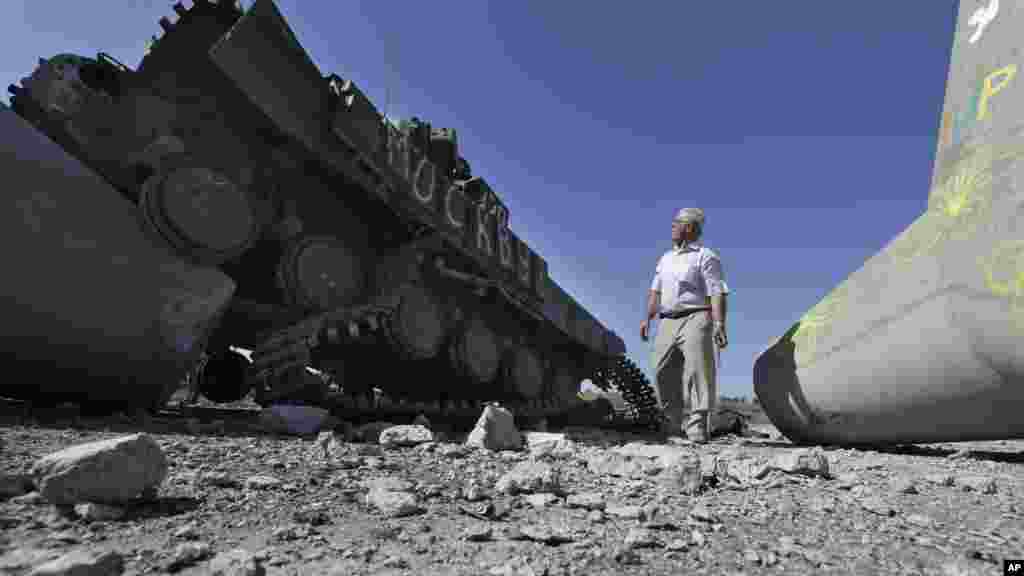 Seorang pria melihat sebuah tank militer Ukraina yang hancur dekat desa Lebedynske, di jalan layang yang menggabungkan Mariupol dan Novoazovsk, Ukraina (6/9).&nbsp;(AP/Sergei Grits)