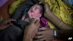 Newly arrived Rohingya Muslim parents from Myanmar hold their newborn baby girl after having just crossed over the border, as they wait for permission to proceed towards a refugee camp in Bangladesh, Nov. 11, 2017.