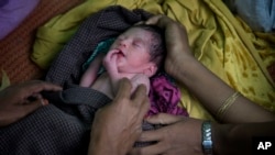 지난해 11월 미얀마를 탈출해 방글라데시로 피난한 로힝야족 난민 부부가 갓 태어난 신생아 딸을 안고 난민촌에 들어가기 위한 허가서를 기다리고
있다.