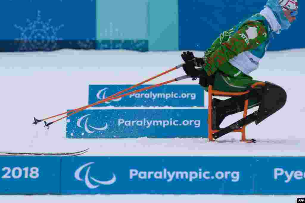 An athlete skis past signs at the nordic skiing venue of the Pyeongchang Paralympic games, in Pyeongchang on March 9, 2018.