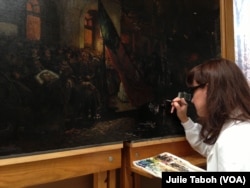 Marta Brassfield, one of the Senior Painting Conservators with Olin Conservation, Inc., uses a fine brush to inpaint damaged areas of “Borne by Loving Hands,” a painting by German artist Carl Bersch that captures the aftermath of President Abraham Lincoln's assassination.