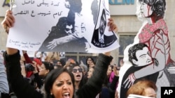 An Egyptian protester chants anti interior ministry slogans as she holds a poster of Shaimaa el-Sabagh, an activist who was shot dead at a small peaceful protest last Saturday, with Arabic that reads, " how many martyrs remaining for victory," during a wo
