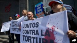 2019年7月15日反對派活動人士在聯合國開發計劃署駐加拉加斯辦事處外抗議活動；西班牙語標語上寫著“共同反對酷刑”。