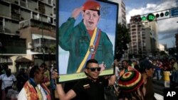 A government supporter carries a painting of Venezuela's late President Hugo Chavez in Caracas, Venezuela, Tuesday, Jan. 5, 2016, to protest the swearing-in of opposition lawmakers. (AP Photo/Alejandro Cegarra)