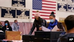 Дві жінки в захисних масках через пандемію COVID-19 голосують на виборчій дільниці в середній школі Віндхем, штат Нью-Гемпшир, 3 листопада 2020 р. (Charles Krupa/AP)