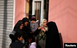 FILE - Women gather near a house during a specialized operation in a Roma neighborhood in the city of Pazadzhik, Bulgaria, Nov. 25, 2014.