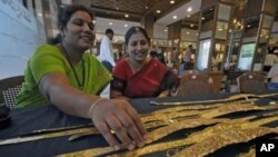 A woman browses gold waist belts at a jewelery shop during the Akshaya Tritiya festival in the southern Indian city of Hyderabad May 6, 2011.