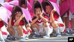 Anak-anak Taiwan berlindung dari sinar matahari dalam latihan perayaan Hari Nasional (8/10) di Taipei. 