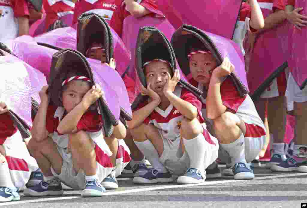 Taiwanese children cover their heads to keep from the sun during a rehearsal for National Day celebrations in front of the Presidential Office in Taipei, Taiwan. National Day is known as Double-Ten, because it falls on October 10, the tenth day of the tenth month of the year. It commemorates the Republican Revolution, which broke out in Wuhan, China, on Oct. 10, 1911, and brought about the end of China's Qing dynasty.
