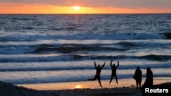 FILE - Teenagers goof off as the sun sets in Encinitas, California, March 31, 2014. 