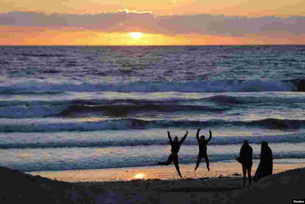 Teenagers pose while having their pictures taken with a phone as the sun sets in Encinitas, California, USA, Mar. 31, 2014.